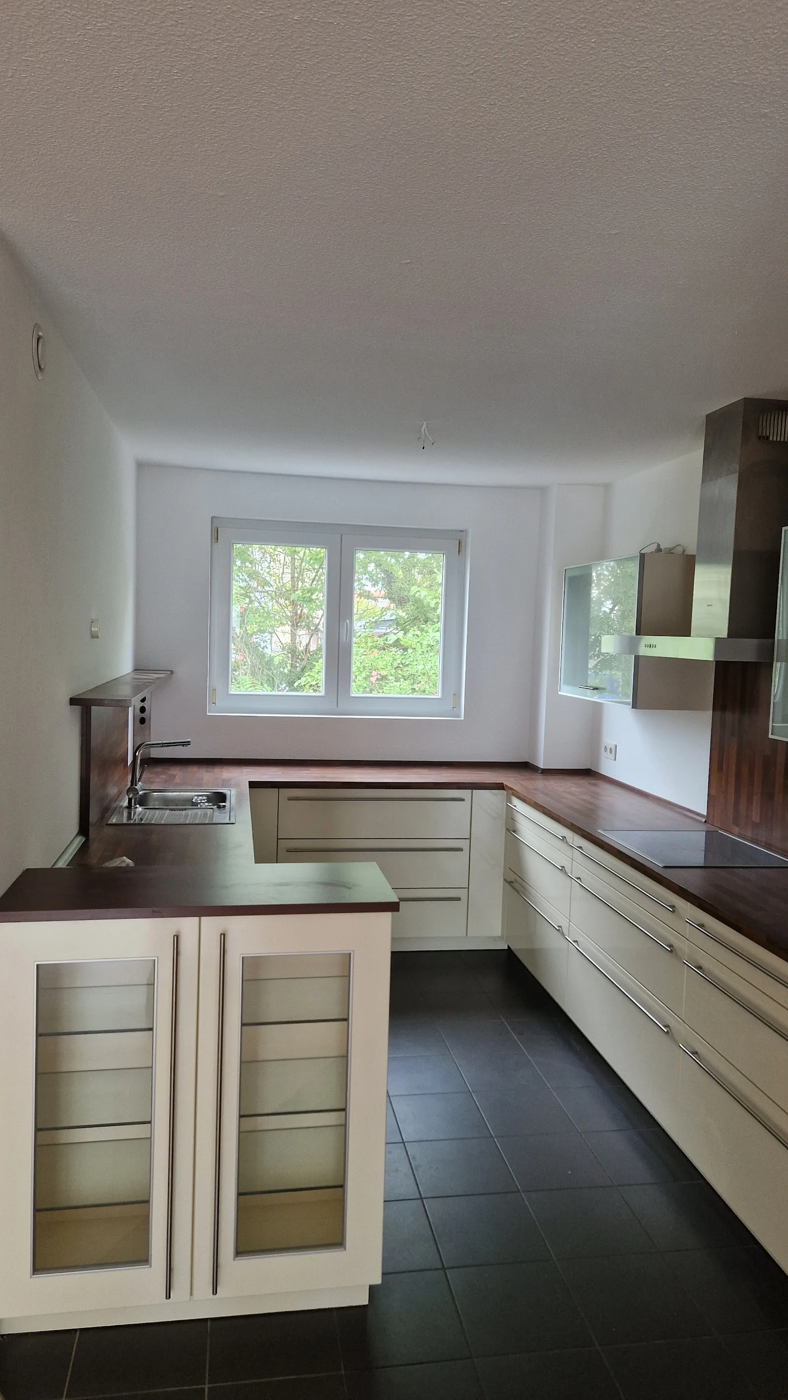 Küche mit cremefarbenen Fronten und dunklem Fliesenboden