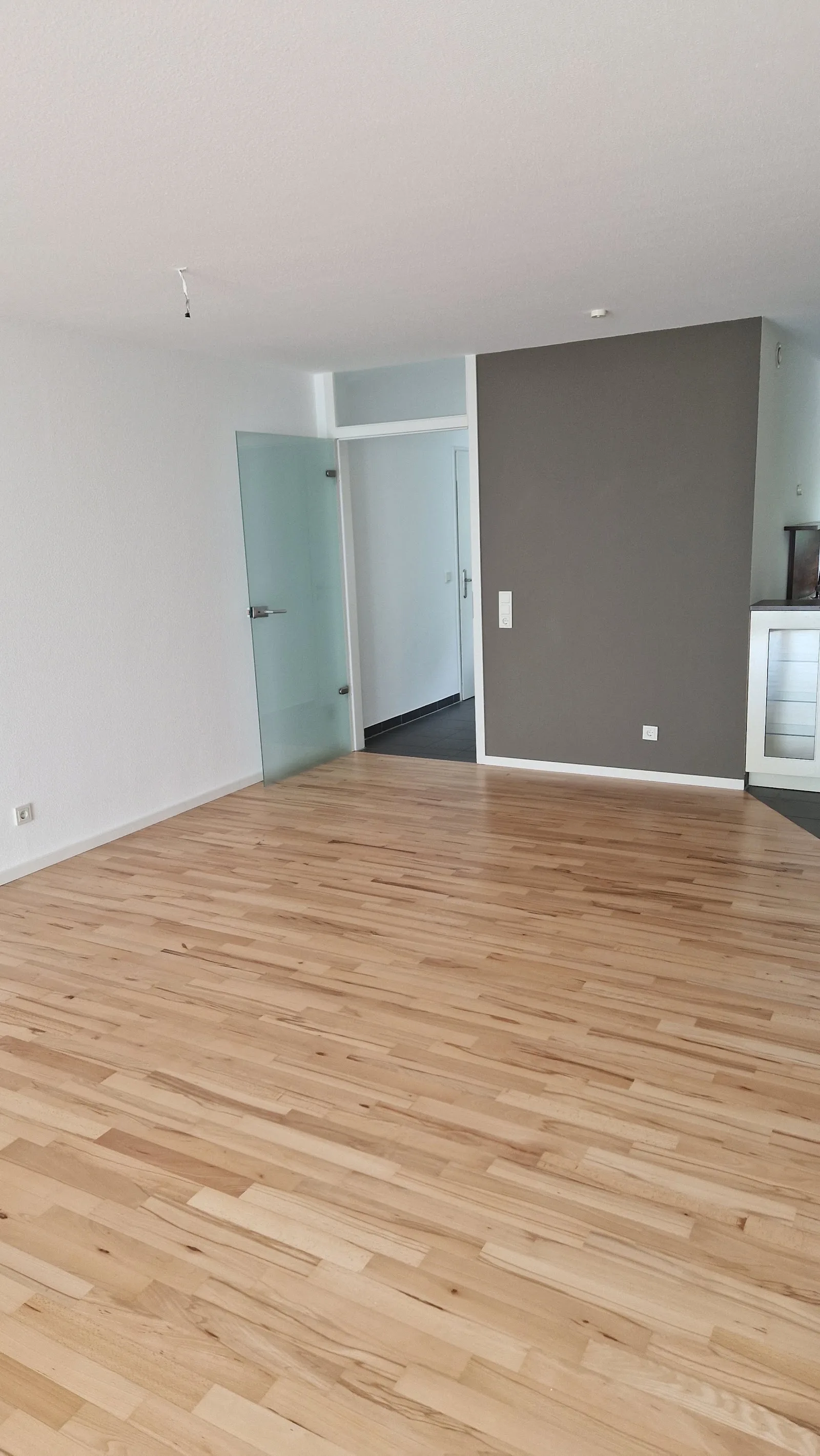 Frisch verlegtes helles Parkett in leerem Wohnraum mit grauer Wandfarbe